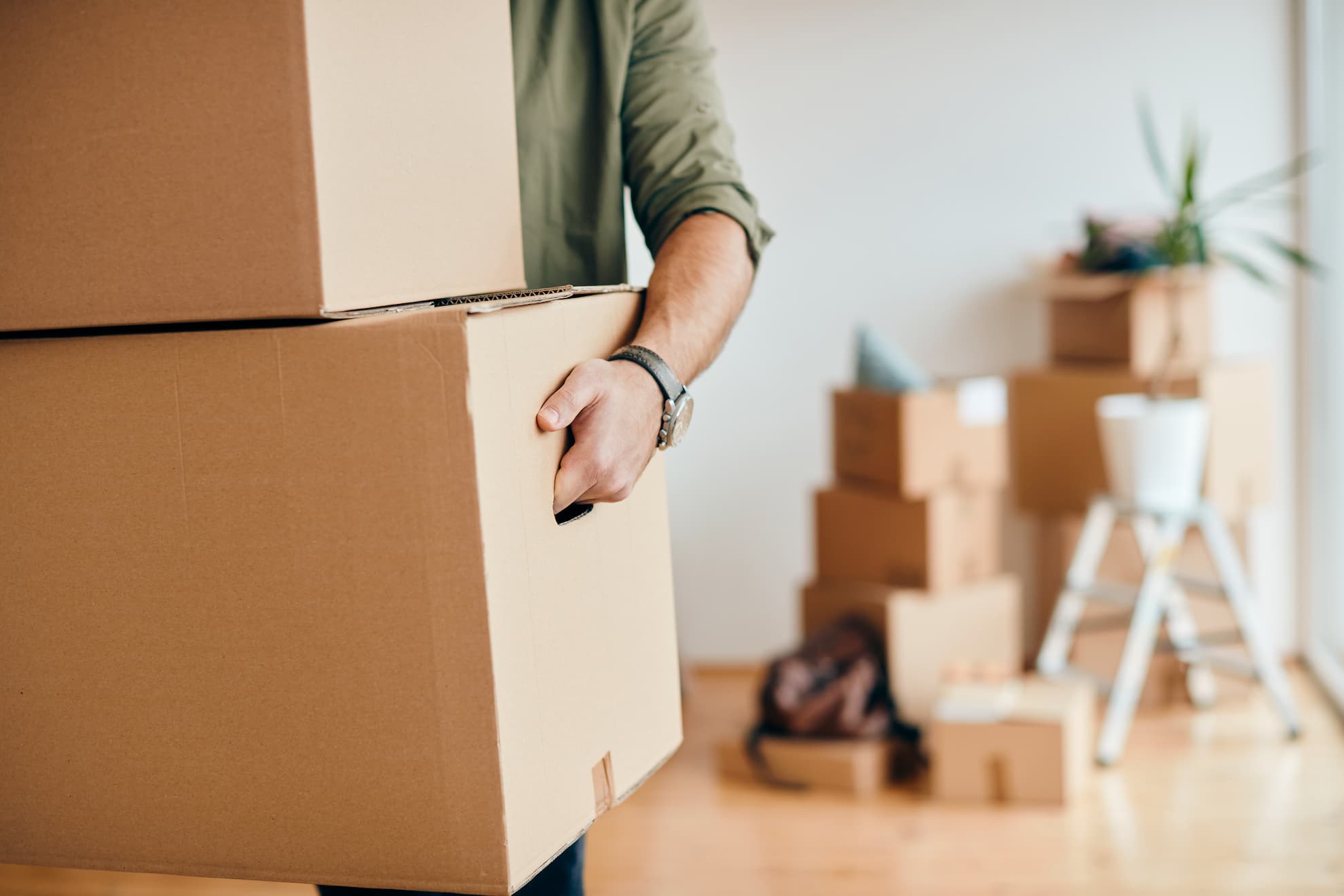 closeup man carrying cardboard boxes while relocating into new apartment 2